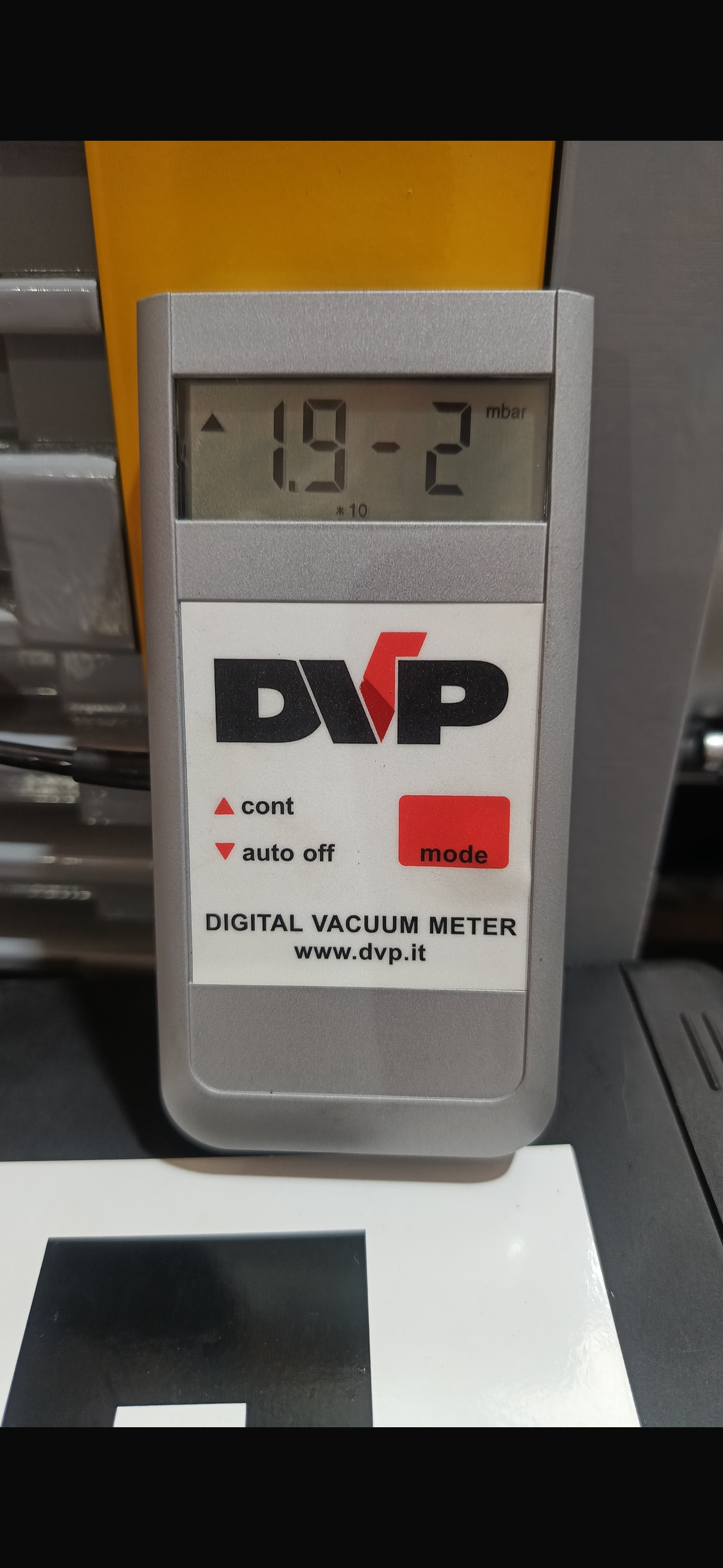 Digital vacuum meter showing 0.019 mbar during a rotary vane vacuum pump field test