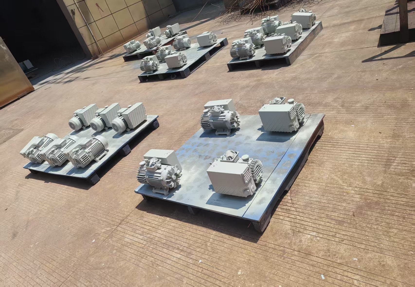 Cream-colored rotary vane vacuum pumps arranged on pallets outside the workshop