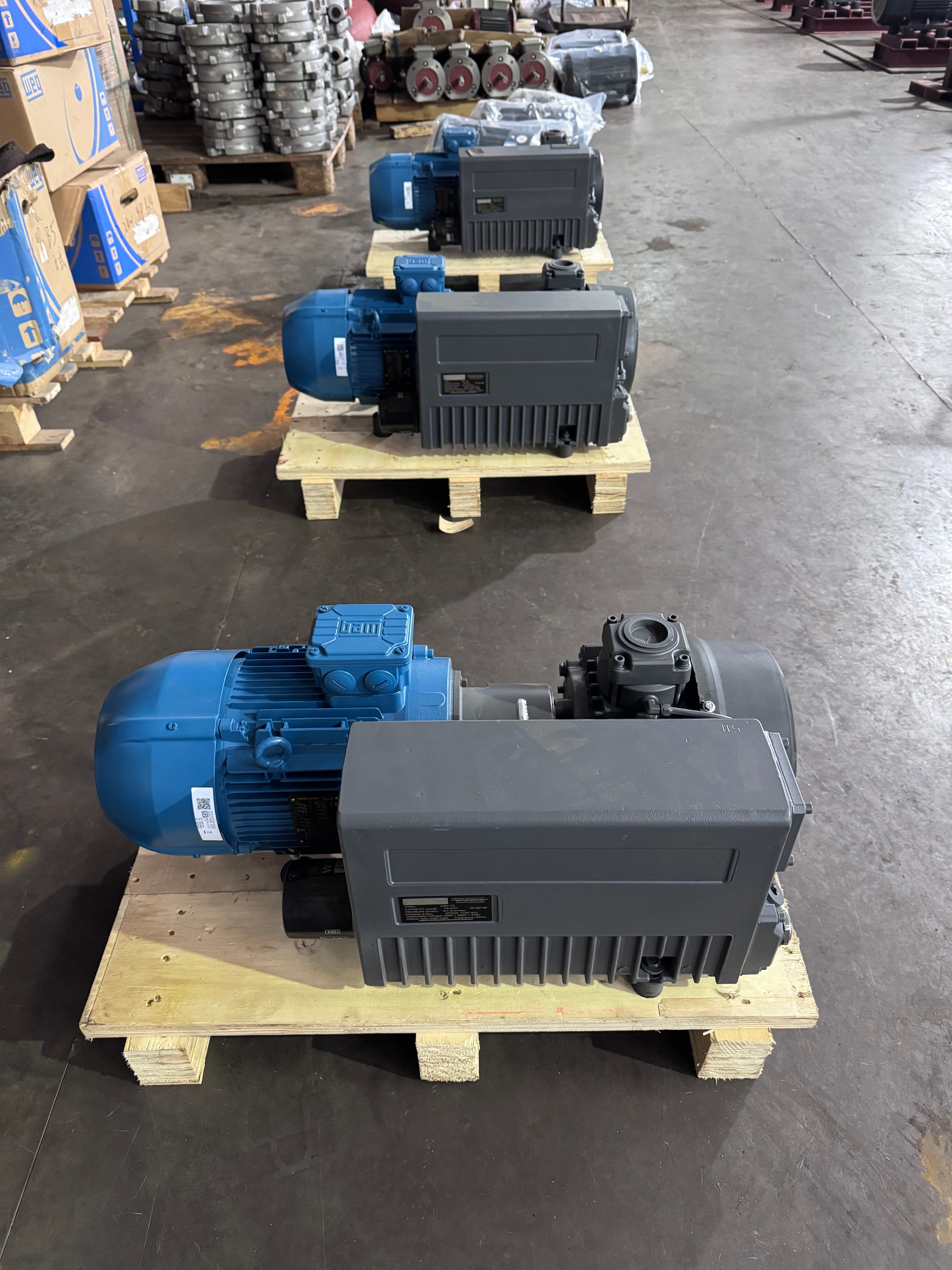 XMV Series oil-sealed rotary vane vacuum pump — blue units on production line